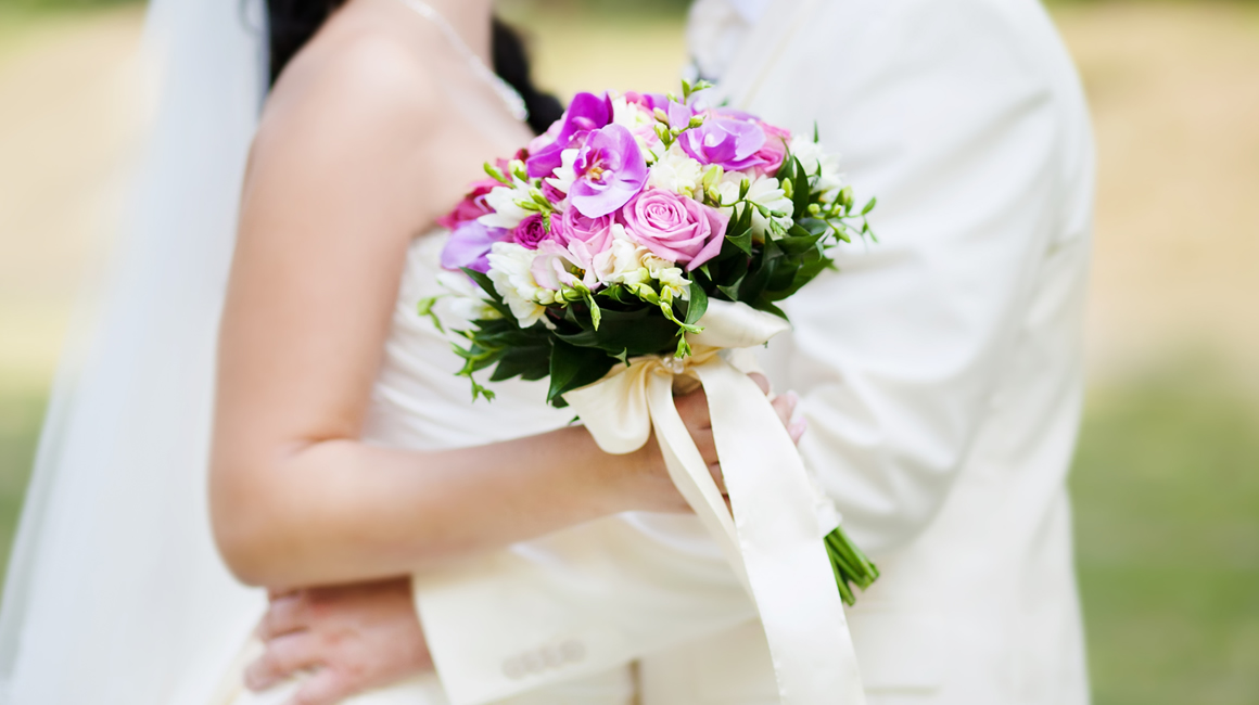 Bride standing with her groom with a bouquet of flowers in her hand